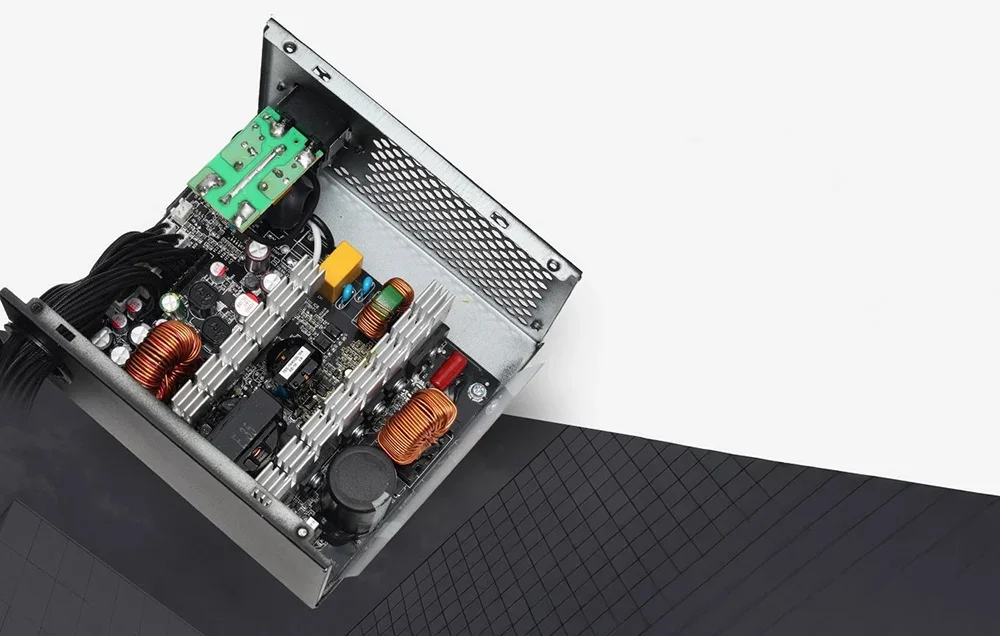 Barošanas bloka iekšpuse ar redzamām elektroniskām shēmām un vara spolēm