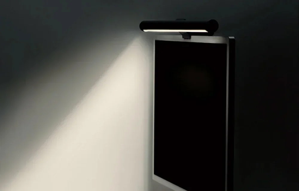 Desk light bar lamp mounted on the top edge of the monitor, illuminating the wall at an angle